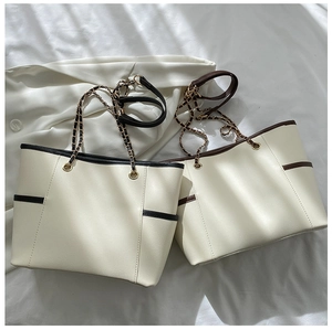 Detail of chic tote bag with chain strap and side pockets in black and brown finishes