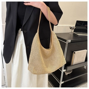 Detail of a beige hollow-out woven hobo bag featuring leather straps for summer travel