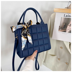 Détail du sac à main bleu marine à motif gaufré avec un foulard en soie élégant