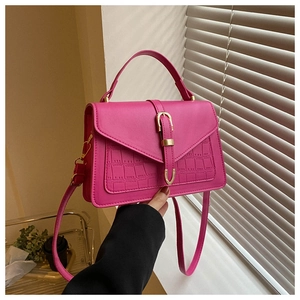 Detail of a bright pink PU leather Kelly bag with crocodile pattern and golden metal buckle