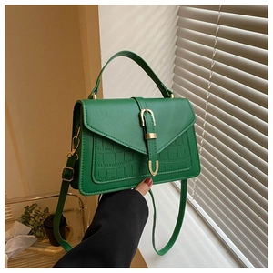 Detail of green faux leather bag with crocodile pattern texture and golden metal buckle