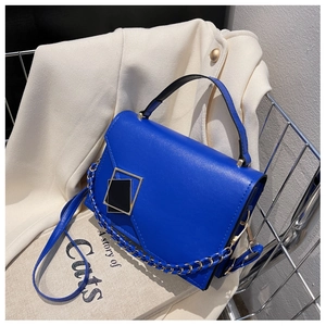 Detail shot of blue crossbody bag with gold buckle and chain edge on a white jacket