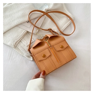 Detail of creative shirt-shaped crossbody bag featuring a golden coat hanger handle
