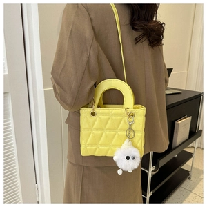 Detail of yellow quilted mini crossbody bag with cute white plush monster charm