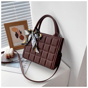Détail d'un sac à main marron foncé gaufré avec un foulard en soie décoratif