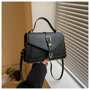 Close-up of black crocodile embossed leather bag featuring elegant gold clasp and handle
