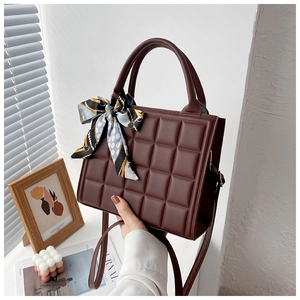 Détail du sac boîte marron foncé avec gaufrage chocolat et poignée élégante en foulard