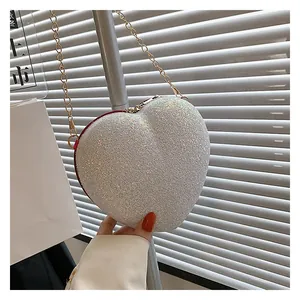 Detail of a heart-shaped crossbody bag with silver glitter finish and red piping