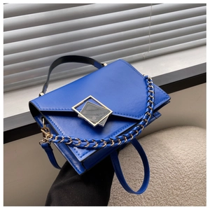 Detail of royal blue leather handbag featuring large gold buckle and metal chain strap