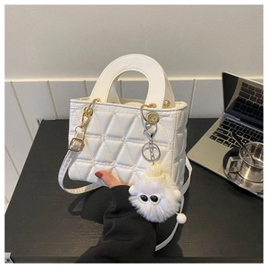 Detail of white quilted handbag with gold hardware and plush monster charm on side