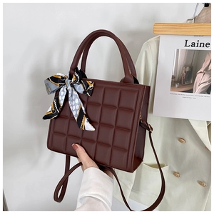 Détail d'un sac à main matelassé marron café avec foulard décoratif et bandoulière fine