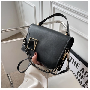 Detail of black matte leather handbag with gold square buckle and chain strap