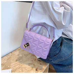 Model wearing a purple quilted crossbody bag with gold chain and metal lock detail