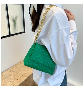 Detail of bright green quilted shoulder bag with chunky gold chain strap on model