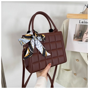 Détail d'un sac à main marron foncé matelassé avec motif à carreaux et foulard en soie décoratif