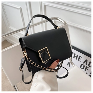 Detail of black matte PU square bag showing golden geometric lock and metal chain strap