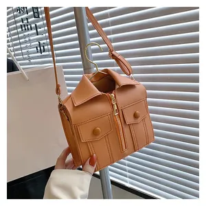 Detail of jacket-style shoulder bag in caramel PU leather with zipper and buttons
