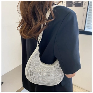 Detail of silver rhinestone hobo bag on shoulder against black blazer backdrop