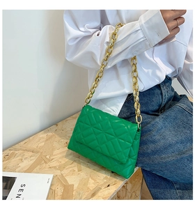Detail of green quilted handbag featuring a bold chunky gold acrylic chain strap