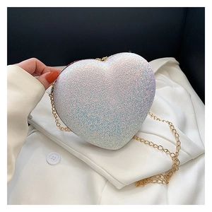 Detail of a mini heart-shaped iridescent evening clutch with a gold metal chain strap