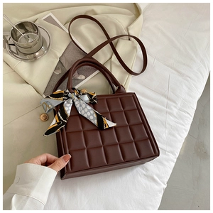 Détail d'un sac à main matelassé marron foncé avec foulard en soie sur la poignée