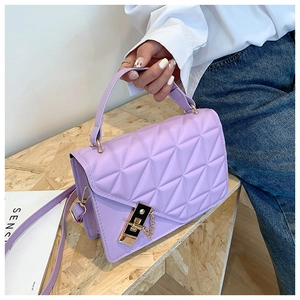 Close-up of lavender quilted handbag with golden metal lock and elegant chain strap details