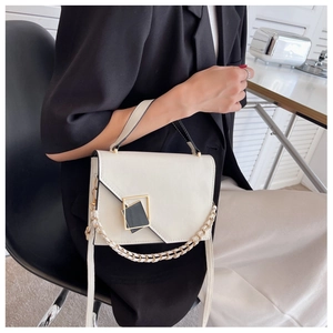 Detail view of white crossbody bag with asymmetric flap and golden metal buckle