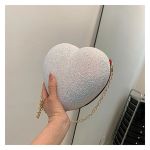 Close-up of heart-shaped glitter evening bag with gold chain and sequin finish