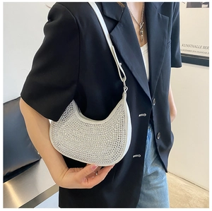Detail of crescent rhinestone underarm bag with sparkling crystals on black blazer background