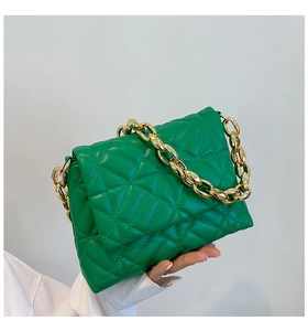 Detail of green quilted PU leather handbag featuring a chunky gold acrylic chain handle