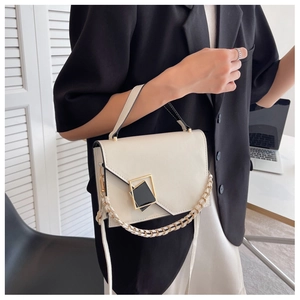Detail of minimalist beige crossbody bag featuring geometric metal buckle and chain strap