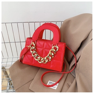 Detail of red quilted PU leather handbag with chunky gold chain and strap on blazer