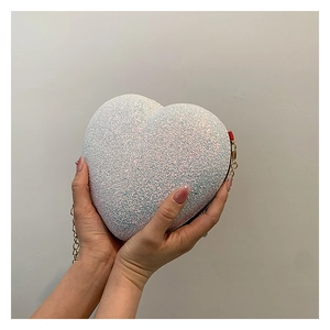 Close-up of heart-shaped glitter clutch bag with elegant gold metal chain strap