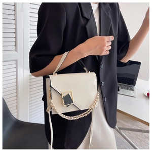 Detail of minimalist cream square handbag with decorative gold-rimmed black buckle
