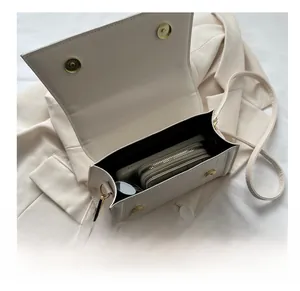 Interior view showing the large capacity of this cream leather crossbody bag with items