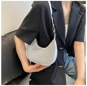 Detailed close-up of a white crescent shoulder bag with silver rhinestones on a black suit