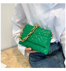Detail of green quilted shoulder bag with chunky gold chain strap and diamond pattern