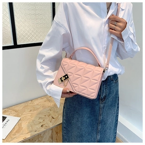 Detailed side view of pink quilted handbag with gold hardware on a crossbody strap
