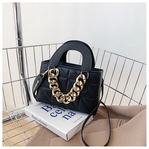 Detail of black quilted leather handbag with thick gold chain in a metal shopping cart