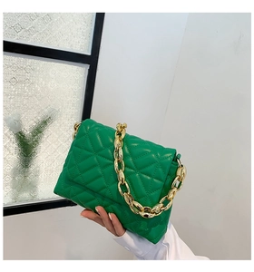 Detail of green quilted PU leather shoulder bag with bold gold acrylic chain strap