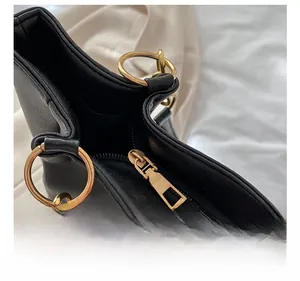 Close-up of premium golden metal zipper and ring hardware on black leather tote bag