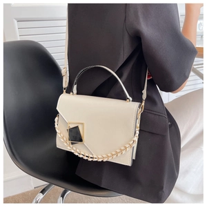 Detail of white PU leather crossbody bag with geometric gold buckle and chain handle