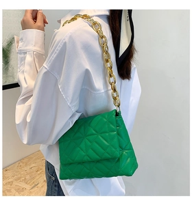Detail of green quilted PU leather shoulder bag with bold gold acrylic chain handle