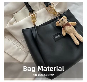 Detail of black PU leather tote fabric with FASHION label and golden chain strap