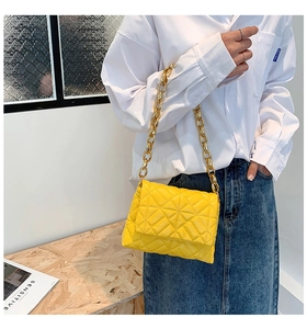Detail of yellow quilted PU leather handbag with chunky gold chain strap on model