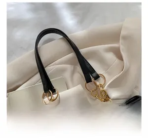 Detail of black tote bag featuring gold metal rings and a cute beige crochet bear charm