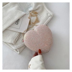 Close-up of pink glitter heart-shaped clutch bag with delicate gold chain strap