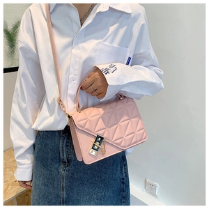 Detail of a pink quilted crossbody bag with gold metal latch and decorative chain strap