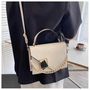 Detail shot of a cream-colored crossbody bag featuring a unique black and gold geometric buckle