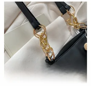 Detail of golden metal buckle and chain strap on black leather tote bag for women